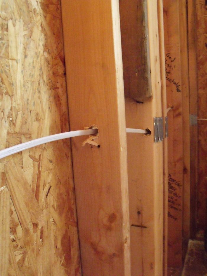 Ruwbouw met houten stijlen: een witte kabel loopt door geboorde gaten.